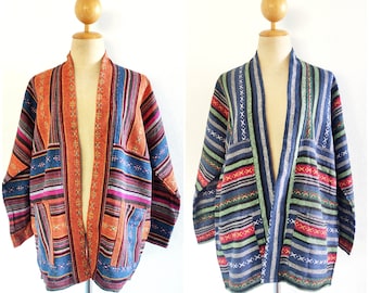 May include: Two long-sleeved, open-front jackets with colorful striped patterns. The jacket on the left is orange, blue, and pink. The jacket on the right is blue, green, and red.