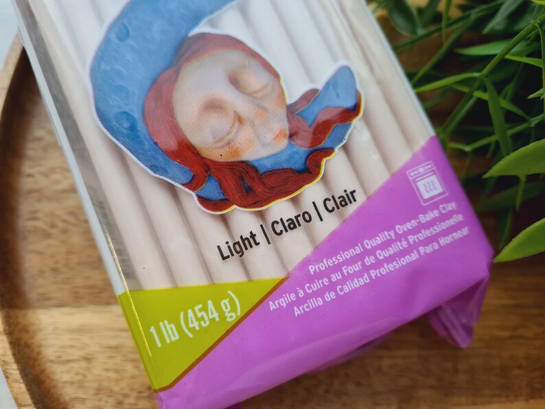May include: A package of light-colored oven-bake clay. The package is labeled with the text "1 lb (454 g)", "Light | Claro | Clair", and "Professional Quality Oven-Bake Clay".