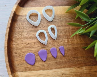 May include: Set of six white plastic flower cutters and four purple fondant flower shapes on a wooden surface.