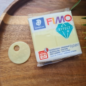 May include: A package of yellow FIMO Effect modeling clay with a diamond logo and the text "STAEDTLER" and "FIMO EFFECT". The package also includes instructions for baking the clay at 110°C (230°F).