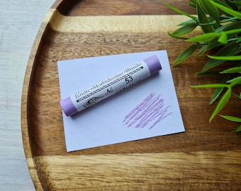May include: A purple pastel stick with the text "Tendre - Morbidissimo - Blando" and "No. 53" on the label. The pastel is on a white piece of paper with a purple mark made by the pastel.