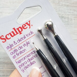 Puede incluir: Un paquete de herramientas de estilo y detalle Sculpey. El paquete muestra tres herramientas con mangos negros y puntas de metal plateado. Las herramientas son para esculpir y detallar arcilla polim&eacute;rica.