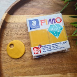 Könnte beinhalten: Eine Packung gelber FIMO Effect Modelliermasse. Die Packung trägt den Markennamen "FIMO" und den Text "Modelliermasse ofenhärtend 57 g (2 oz) e Modelling clay oven-bake Pâte à modeler cuire au four Pasta de modelar endurecer al horno".