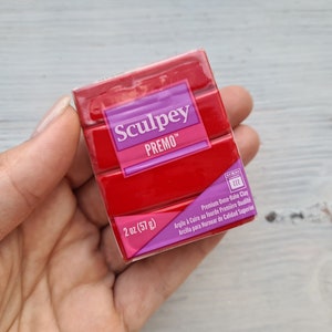 Könnte beinhalten: Eine 57 Gramm Packung roter Sculpey Premo Backofen-Modelliermasse. Die Packung ist mit dem Markennamen, dem Produktnamen, dem Gewicht und den Anweisungen zum Backen der Masse beschriftet.