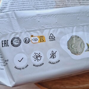 Pode incluir: Uma embalagem branca com uma marca de verifica&ccedil;&atilde;o, as palavras "Pronto a usar", "Lav&aacute;vel" e "Sem gl&uacute;ten", e um s&iacute;mbolo de reciclagem. A embalagem tamb&eacute;m tem o texto "Conforme ASTM D-4236", "Eac" e "FR".