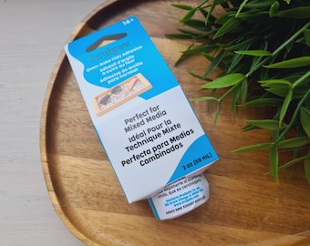 May include: A blue and white box of Sculpey Oven-Bake Clay Adhesive. The packaging features the text Oven-Bake Clay Adhesive, Perfect for Mixed Media, and 2 oz (59 mL). The box shows a small rectangular tray with clay pieces inside.