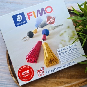 May include: A box of Fimo Leather Effect modeling clay with four 25-gram packs. The box shows a red and yellow tassel keychain with a key ring and beads. The box also includes the text "Tassel Kit. Quasten Set Kit Tassels. Set Borlas".