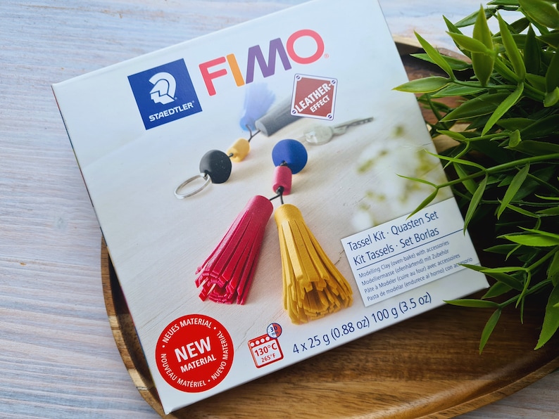 May include: A box of Fimo Leather Effect modelling clay with four 25-gram packs. The box shows a red and yellow tassel keychain with a key ring and beads. The box also includes the text "Tassel Kit. Quasten Set Kit Tassels. Set Borlas".