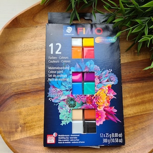 May include: A box of Staedtler FIMO Professional polymer clay with 12 colors. The box features a floral design and the text "12 Farben Colours Couleurs Colores". Each clay block is 25 g (0.88 oz).