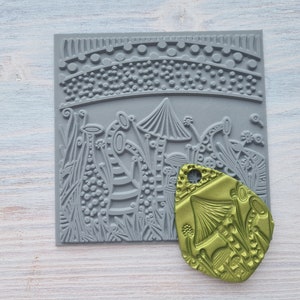 May include: A gray rubber stamp with a design of mushrooms and plants. A green rubber stamp with a mushroom design is also shown.