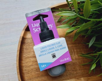 May include: A bottle of Liquid Polymer Clay by Sculpey in a charcoal metallic color. The bottle is labeled with the product name, instructions, and a 14+ age recommendation. The bottle is 1 fluid ounce (30 ml).