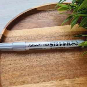 Marcador de tinta metálica Artline 900XF, PLATA, 2,3 MM, ideal para decorar y escribir sobre cartón, plástico, vidrio, metal o cerámica.