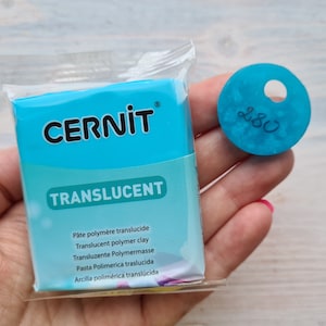 May include: A package of translucent polymer clay by the brand Cernit. The package is blue and white and has the text "CERNIT" and "TRANSLUCENT" on it. The text on the package is in multiple languages. A small blue disc with the number 280 on it is also shown.