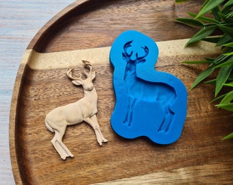 May include: A blue silicone mold of a standing deer, next to a wooden deer figurine.