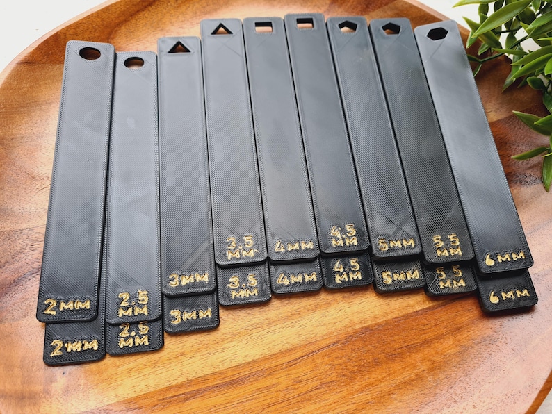Peut inclure: Ensemble d'outils noirs et rectangulaires avec des formes vari&eacute;es en haut, comme un cercle, un triangle et un carr&eacute;. Chaque outil est &eacute;tiquet&eacute; avec du texte dor&eacute; indiquant des mesures de 2 mm &agrave; 6 mm.