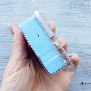 May include: A rectangular block of light blue clay, encased in a clear plastic package. The clay has a textured surface and appears to be a craft or art supply. The packaging is partially visible, showing the product's presentation.