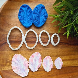 May include: A set of silicone molds for making flower-shaped decorations. The set includes two large blue molds, five white oval molds, and five pink flower molds.