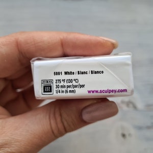 May include: A white Sculpey clay package with text including "5001 White", baking instructions at 130&deg;C for 30 minutes, and 6 mm thickness. The website www.sculpey.com is also visible.