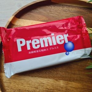 May include: A red and white Premier branded package. The package features the word "Premier" in white lettering and a blue sphere graphic. Japanese text is also visible on the package.