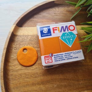 May include: Orange FIMO Effect modeling clay in a package with the brand name and instructions. The clay is oven-bake and comes in a 57 gram package.