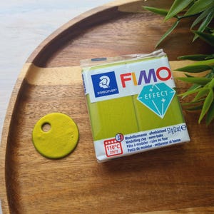 May include: A package of green FIMO Effect modeling clay. The package is labeled with the brand name, FIMO, and the words "Effect" and "Modeling Clay". The package also includes instructions for baking the clay.