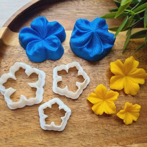 Può includere: Un set di stampini per biscotti a forma di fiore blu e bianco e fiori di pasta di zucchero gialli. Gli stampini per biscotti sono in plastica e i fiori di pasta di zucchero sono di zucchero.