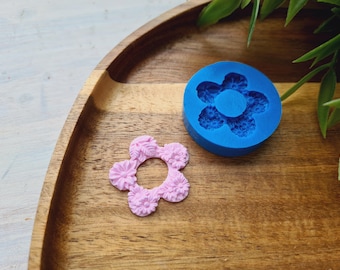 May include: Two silicone molds for making resin crafts. One mold is blue and the other is pink. Both molds are shaped like a flower with five petals.