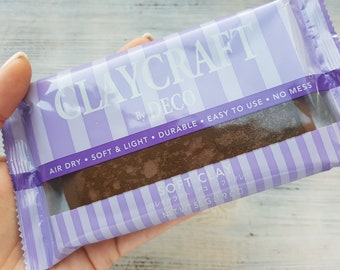 Può includere: Un pacchetto di argilla marrone ad asciugatura all'aria etichettato "CLAYCRAFT by DECO SOFT CLAY" con il testo "AIR DRY SOFT & LIGHT DURABLE EASY TO USE NO MESS" e "NET WT 55 G (1.9 OZ)".