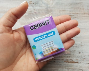 May include: A purple and blue package of CERNIT Number One opaque polymer clay. The package has text in multiple languages.