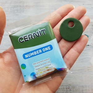 May include: A package of green polymer clay labeled "CERNIT NUMBER ONE" with a small green circle with a hole in the center.