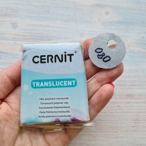May include: A package of translucent polymer clay by Cernit. The package is white with blue lettering and the word "Translucent" in a larger font. The package is labeled with the number 80.