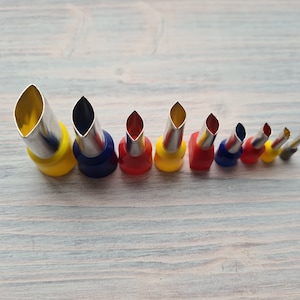 May include: A set of 10 leaf-shaped metal cookie cutters with yellow, red, and blue handles. The cutters are arranged in order of size, with the largest cutter on the left and the smallest cutter on the right.