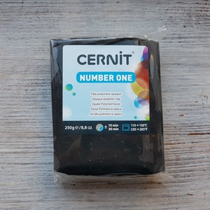 May include: A package of black Cernit Number One polymer clay, weighing 8.8 oz. The package includes instructions for baking the clay at 230-265°F for 10-30 minutes. The package also includes the words "Pâte polymère opaque" and "Opaque polymer clay."