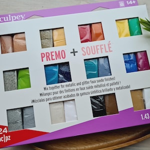 May include: A box of 24 Sculpey Premo + Souffle polymer clay bars. The box features a colourful display of the clay bars, with a mix of metallic and glitter faux suede finishes. The box is labelled with the brand name, product name, and weight: 1.43 lb (649 g).