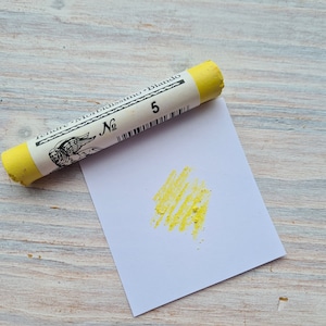 Op de afbeelding: Een gele pastelkrijt met de tekst "Tendre Morbidissimo Blando No. 5" op het etiket. Een klein staaltje gele pastel is op een wit vel papier.