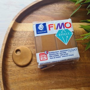 May include: A package of FIMO Effect modeling clay in the color gold. The package shows the brand name FIMO and the text "Effect". The package also includes instructions for baking the clay at 110 degrees Celsius or 230 degrees Fahrenheit.