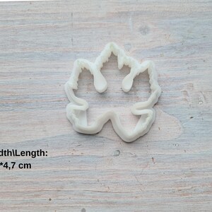 May include: White plastic cookie cutter shaped like a maple leaf. The cutter measures 4.2 inches wide by 4.7 inches long.