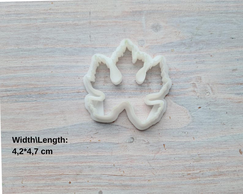 May include: White plastic cookie cutter shaped like a maple leaf. The cutter measures 4.2 inches wide by 4.7 inches long.