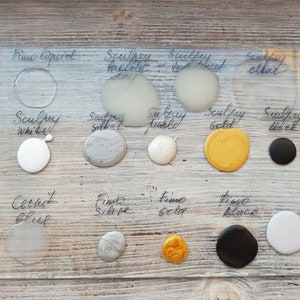 May include: A glass plate with various colors of Sculpey and Fine Silver and Gold paint. The colors include white, silver, gold, black, and a light blue. The plate is labeled with the names of the colors.