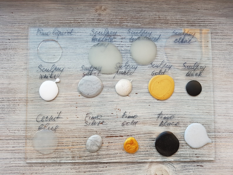 May include: A glass plate with various colors of Sculpey and Fine Silver and Gold paint. The colors include white, silver, gold, black, and a light blue. The plate is labeled with the names of the colors.