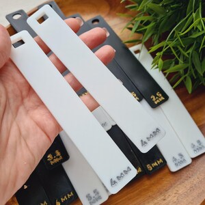 Peut inclure: Plusieurs outils rectangulaires blancs et noirs avec un trou carr&eacute; en haut. Les outils affichent des mesures en millim&egrave;tres : 2,5 mm, 3,5 mm, 4 mm, 4,5 mm et 6 mm.
