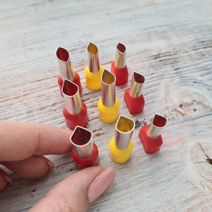 Puede incluir: Un juego de 10 cortadores de galletas de metal con mangos rojos y amarillos. Los cortadores tienen forma de hojas y están dispuestos en círculo sobre una superficie de madera.