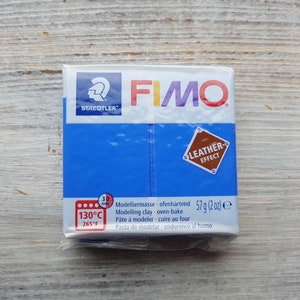 Könnte beinhalten: Eine blaue Packung Fimo Modelliermasse mit Ledereffekt. Die Packung trägt das Staedtler Logo und die Aufschrift "Leder-Effekt" und "57 g (2 oz)".