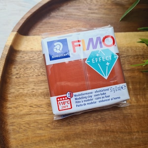 May include: A package of FIMO Effect modeling clay in a terracotta color. The package has the brand name FIMO and the text "Effect" printed on it. The package also includes instructions for using the clay, including the baking temperature of 110°C (230°F).
