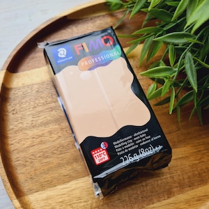 May include: A package of FIMO Professional modeling clay in a light beige color. The package is labeled with the brand name, product name, and instructions for use. The package is 8 ounces (226 grams).