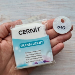 May include: A white package of translucent polymer clay labeled "CERNIT® TRANSLUCENT". The package includes the text "Pâte polymère translucide, Translucent polymer clay, Transluzente Polymermasse, Pasta Polimerica traslucida, Arcilla polimérica translúcida".