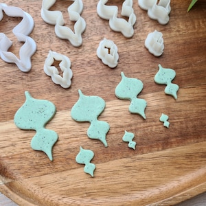 Puede incluir: Un juego de cortadores de galletas de pl&aacute;stico blanco en varias formas, incluyendo flores y hojas, y un juego de cortadores de galletas de pl&aacute;stico verde en varias formas de hojas.