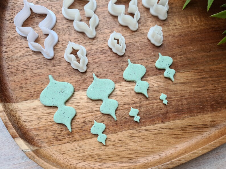 Puede incluir: Un juego de cortadores de galletas de pl&aacute;stico blanco en varias formas, incluyendo flores y hojas, y un juego de cortadores de galletas de pl&aacute;stico verde en varias formas de hojas.
