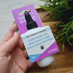 May include: A clear bottle of Liquid Polymer Clay by Sculpey. The bottle is labeled with the product name, instructions, and a 14+ age recommendation. The bottle is 2 fluid ounces (59 ml).