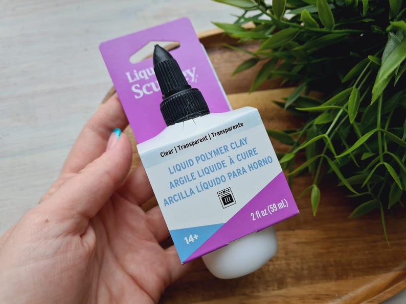 May include: A clear bottle of Liquid Polymer Clay by Sculpey. The bottle is labeled with the product name, instructions, and a 14+ age recommendation. The bottle is 2 fluid ounces (59 ml).